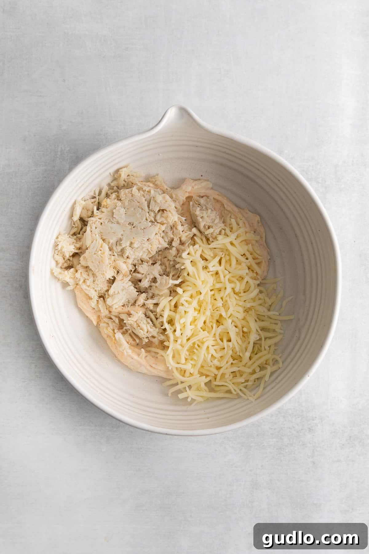 Creamy crab and cheese filling in a white bowl, ready for stuffing mushrooms.