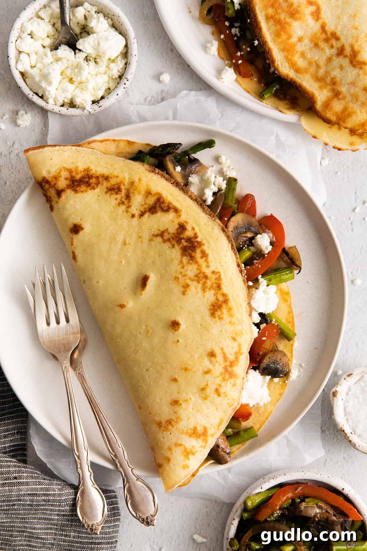 Easy Savory Goat Cheese Crepes with Creamy Filling and Sautéed Vegetables A beautifully plated goat cheese crepe, lightly folded and garnished, with a fork beside it, ready to be enjoyed.