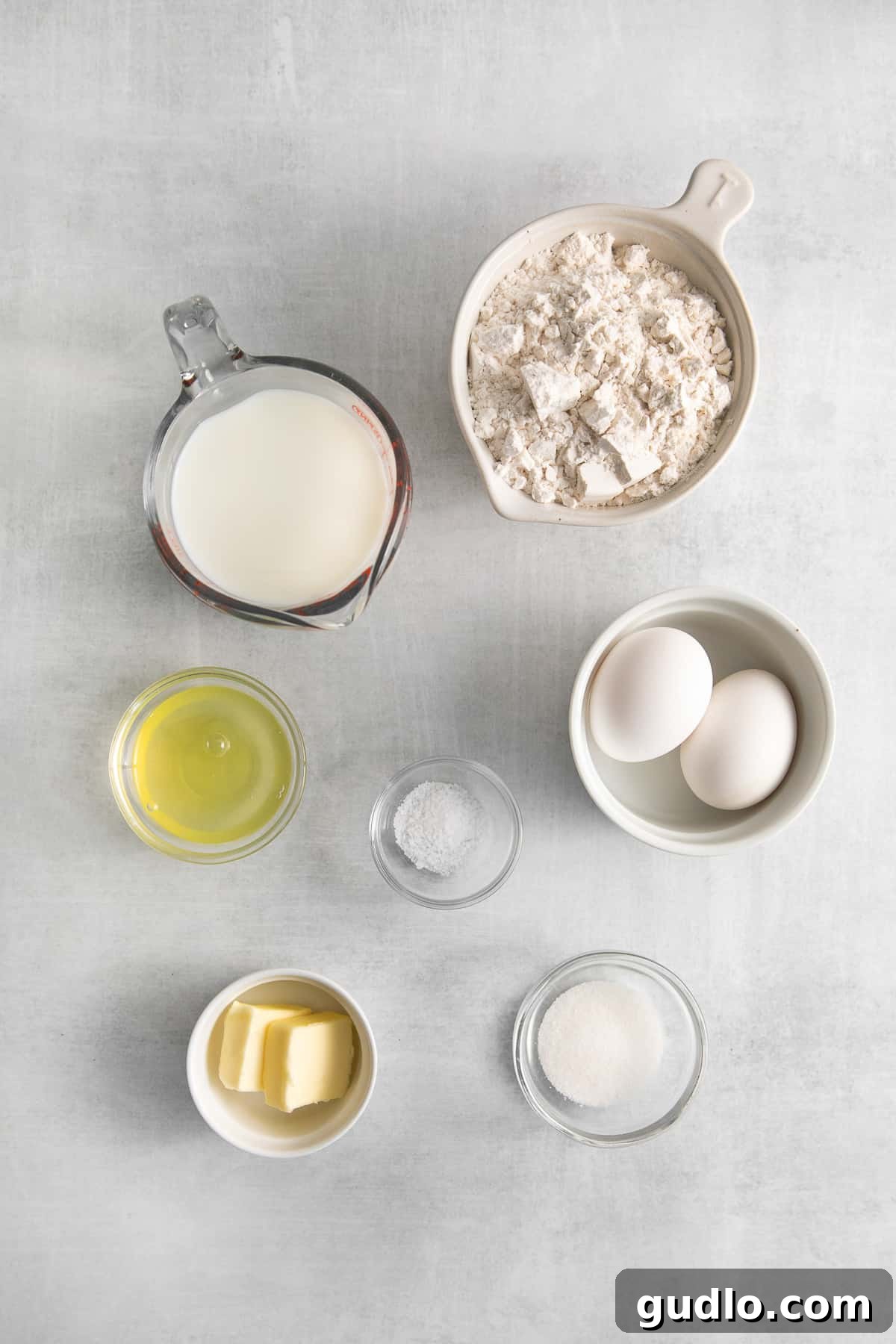 Essential Ingredients for Making Savory Goat Cheese Crepes A flat lay photograph showcasing all the fresh, high-quality ingredients laid out for making goat cheese crepes, including flour, eggs, milk, vegetables, and a block of goat cheese.