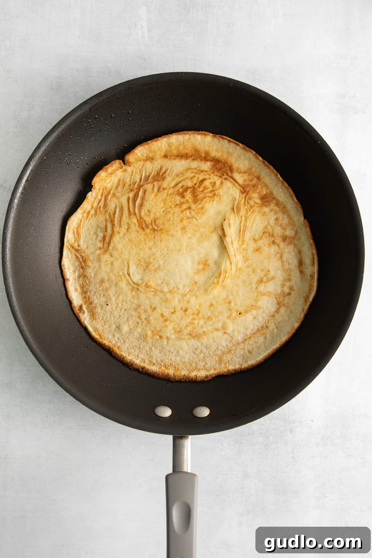 Cooking a Fluffy Goat Cheese Crepe in a Skillet A golden-brown goat cheese crepe cooking in a non-stick skillet, edges perfectly crisping, ready to be flipped.