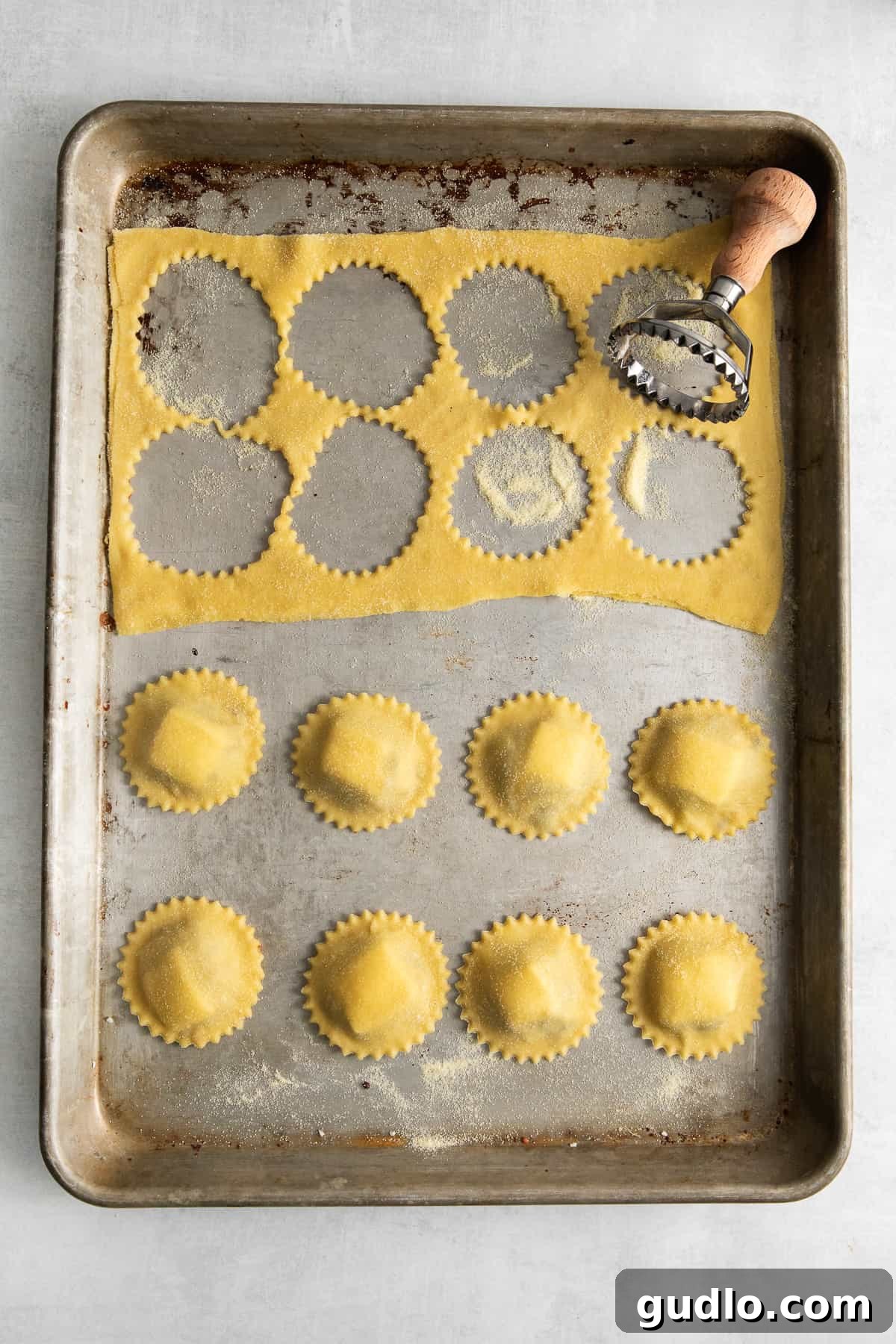 Mushroom ravioli drying on a baking sheet, dusted with flour.