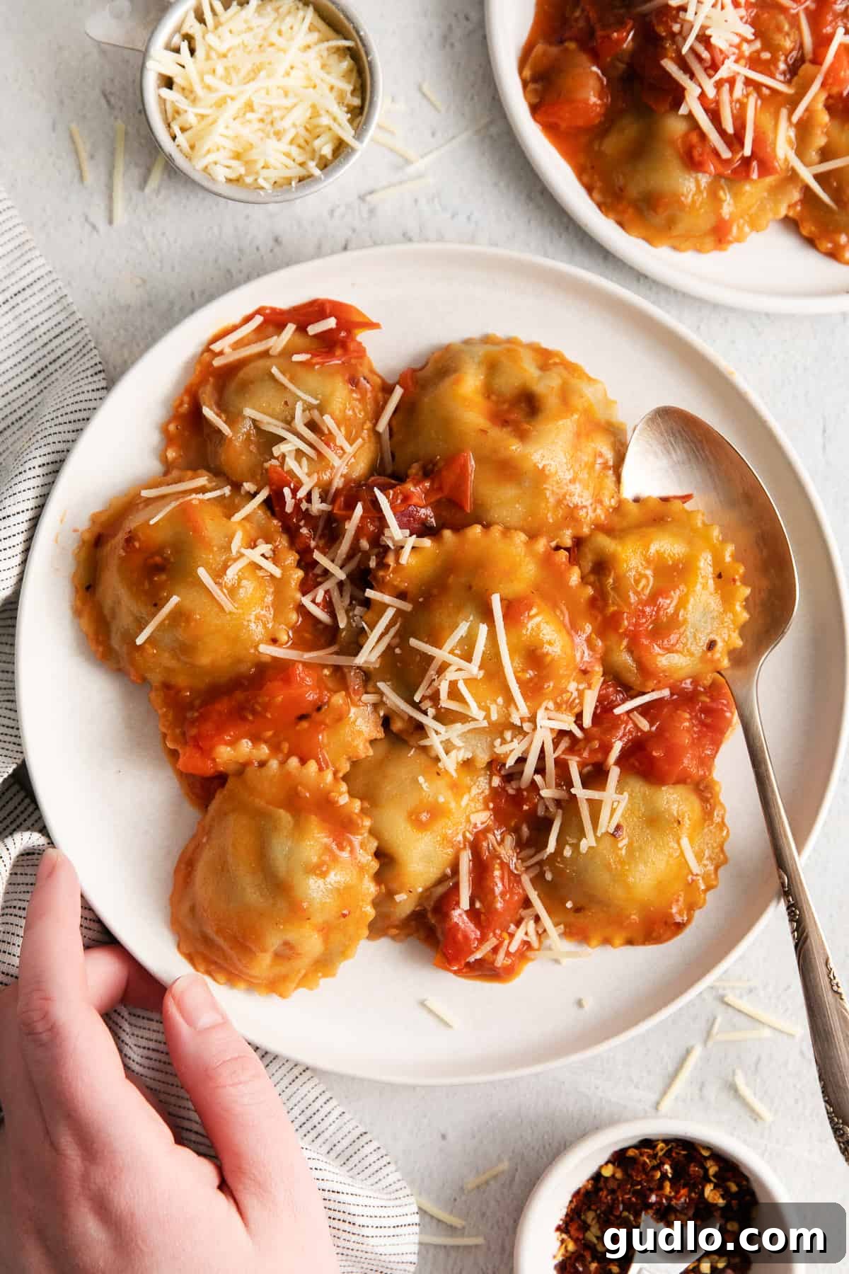 A bowl of fresh mushroom ravioli with red sauce, garnished with herbs.