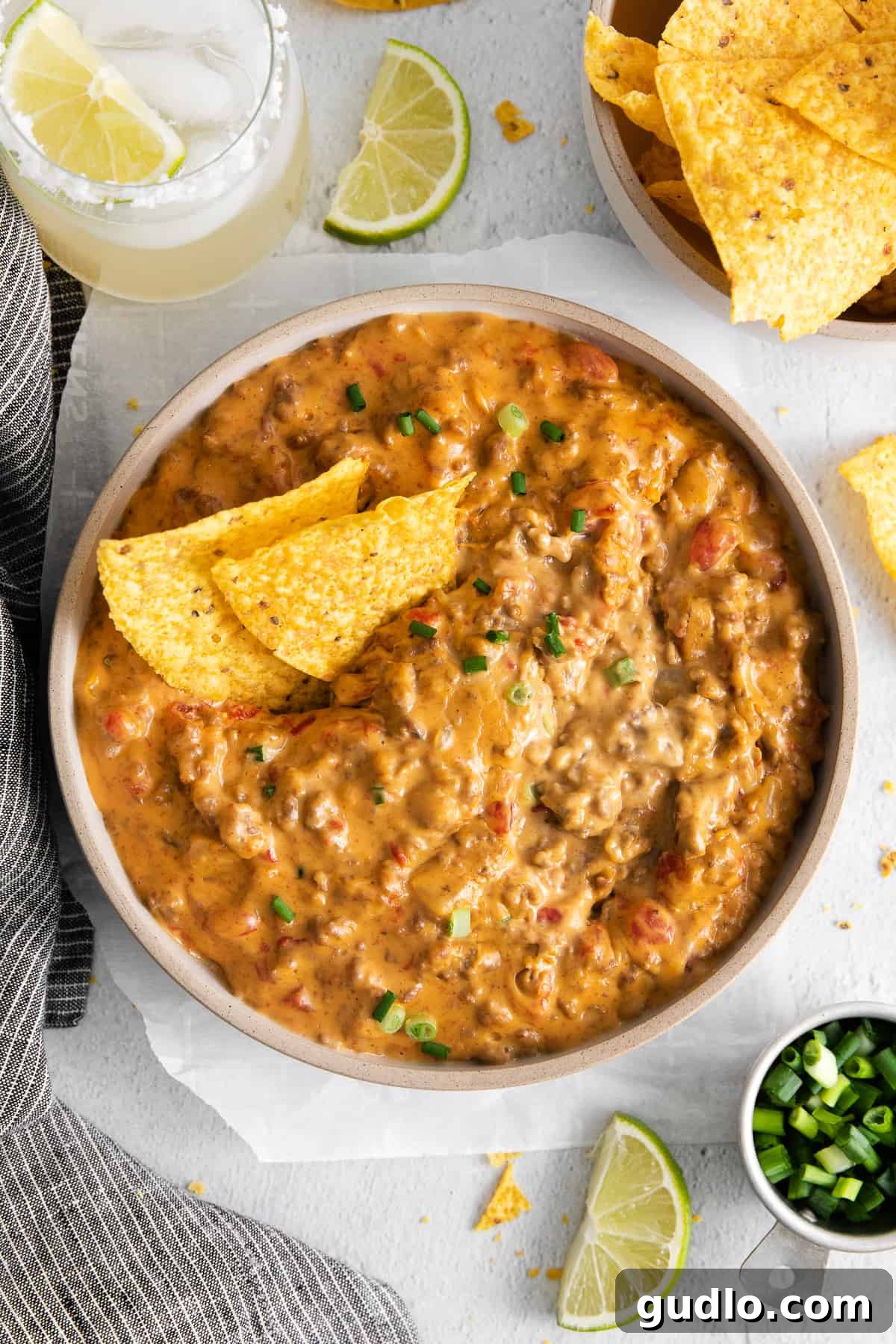 A bowl of hot, bubbling Rotel dip with crispy tortilla chips scattered around it, ready to be enjoyed.