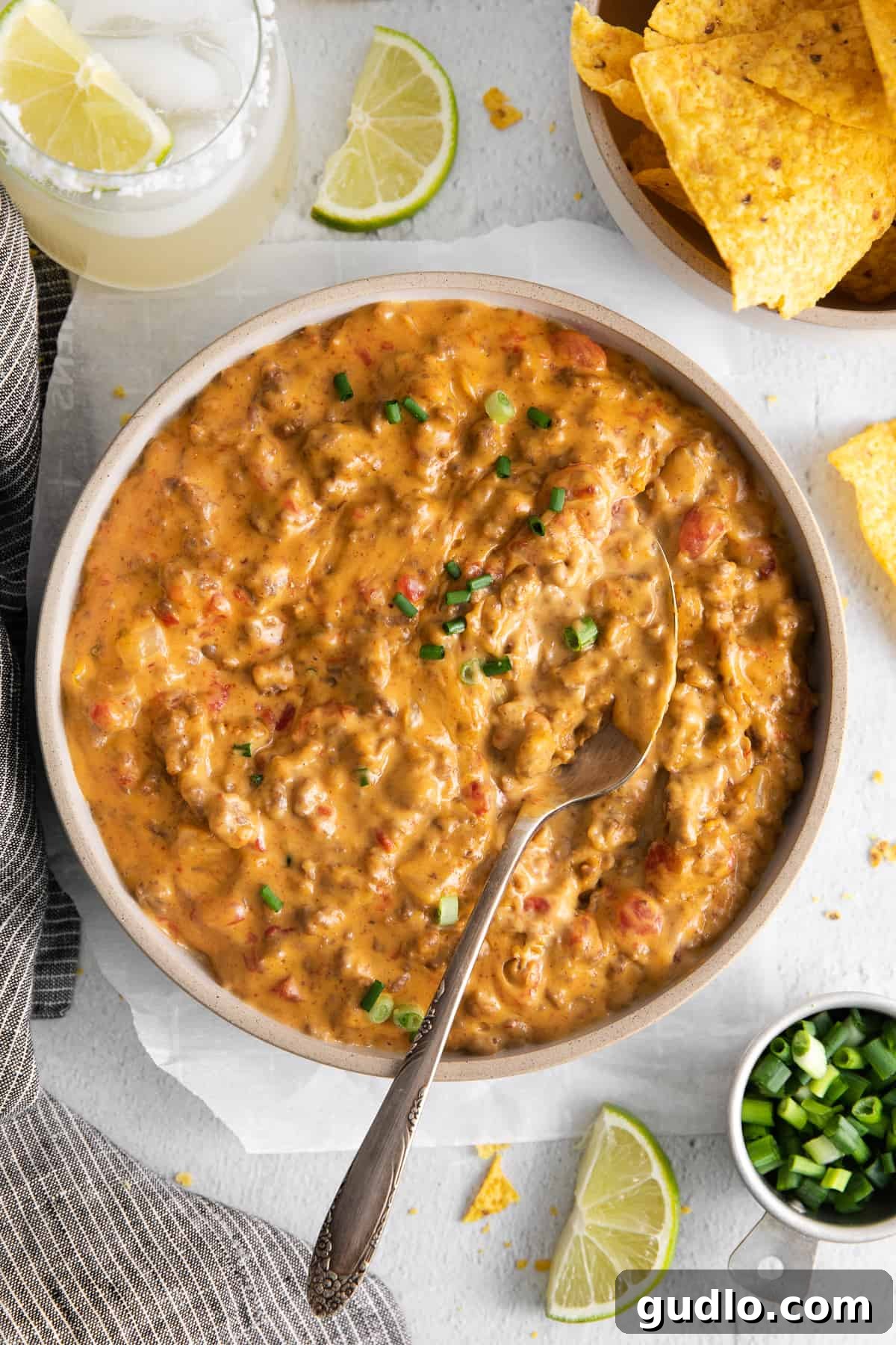 A bowl of hot, creamy Rotel dip with a serving spoon nestled within, ready to be scooped, garnished with fresh cilantro.