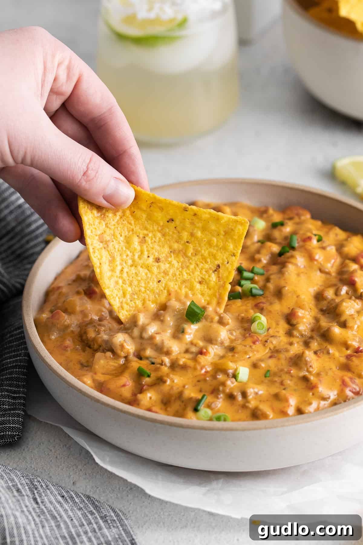 A single tortilla chip generously loaded with warm, golden Rotel dip, showcasing its thick, creamy texture, ready to be eaten.