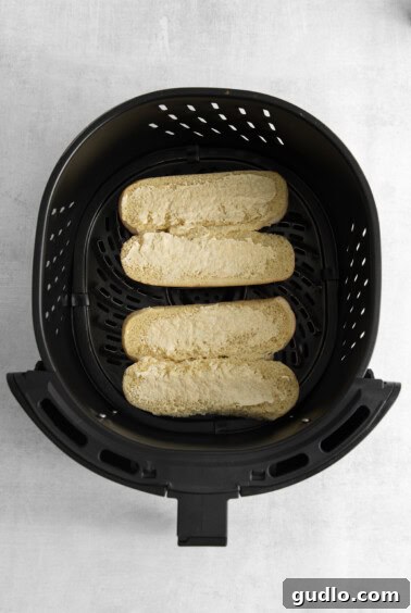 A black air fryer with two cheesy bread slices inside, cooking to a golden perfection.