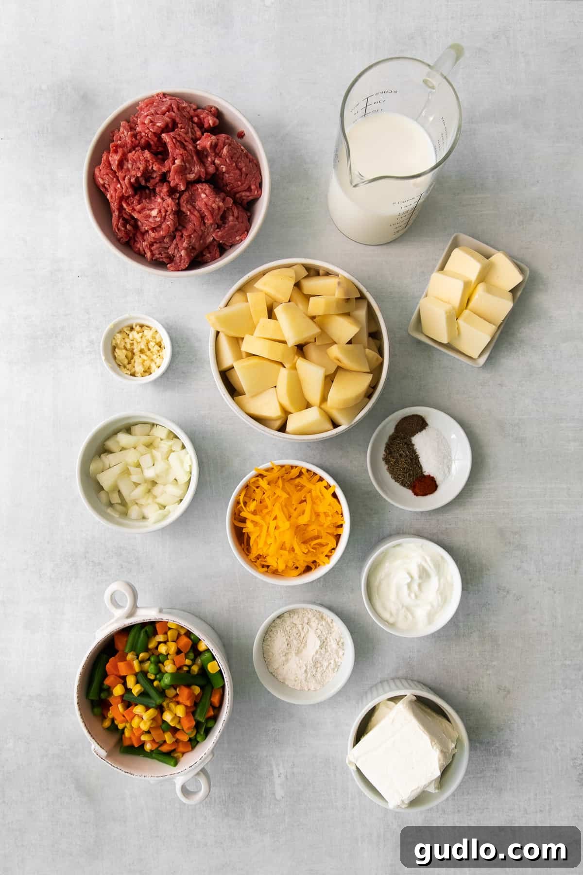 Golden-Topped Cheesy Shepherd's Pie 3 Fresh ingredients laid out for making a cheesy shepherd's pie, including potatoes, butter, cheese, and vegetables.