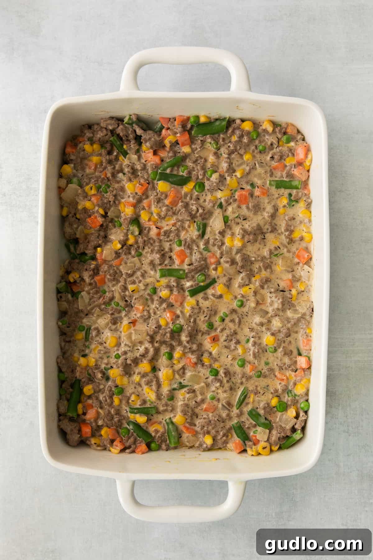 Golden-Topped Cheesy Shepherd's Pie 4 Cooked ground beef and mixed vegetables simmering in a large casserole dish, ready for topping.