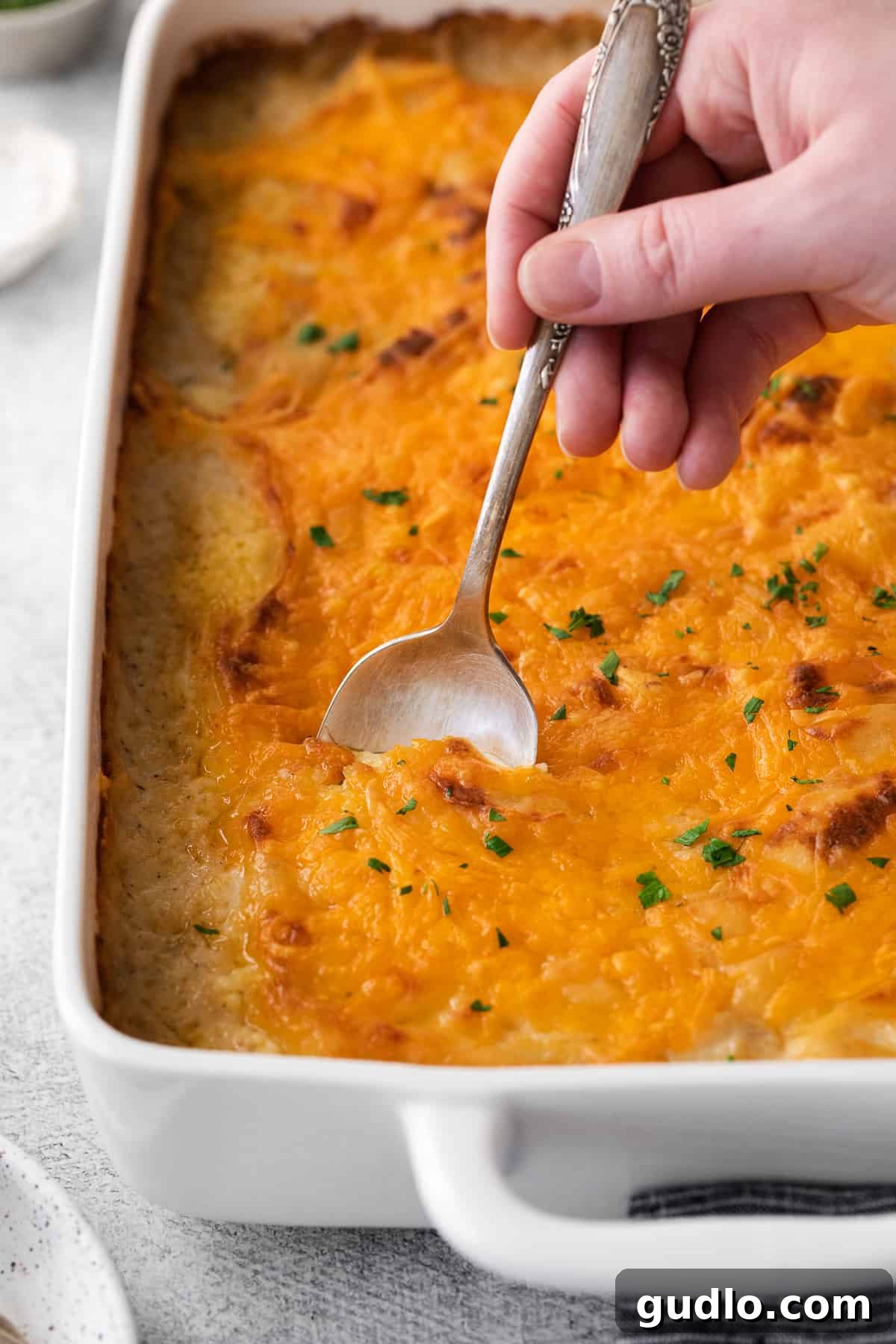 Golden-Topped Cheesy Shepherd's Pie 7 A spoon scooping a generous portion of cheesy shepherd's pie from a casserole dish, revealing the rich layers.