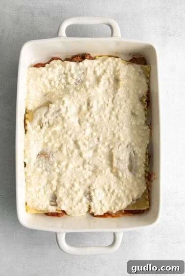Homestyle Cottage Lasagna 12 Layering lasagna noodles, sauce, and cottage cheese in a casserole dish during assembly.