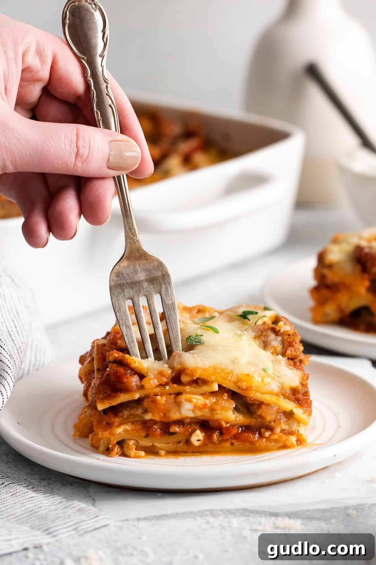 Homestyle Cottage Lasagna 8 A fork taking a delicious bite out of a perfectly baked and garnished piece of cottage cheese lasagna.