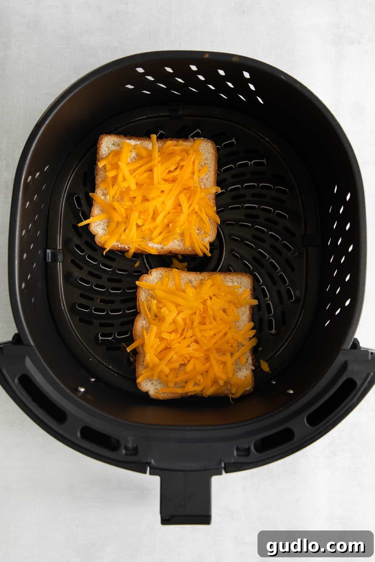 Golden Cheesy Toast 4 Two slices of cheese toast cooking in an air fryer basket, with melted cheese bubbling.