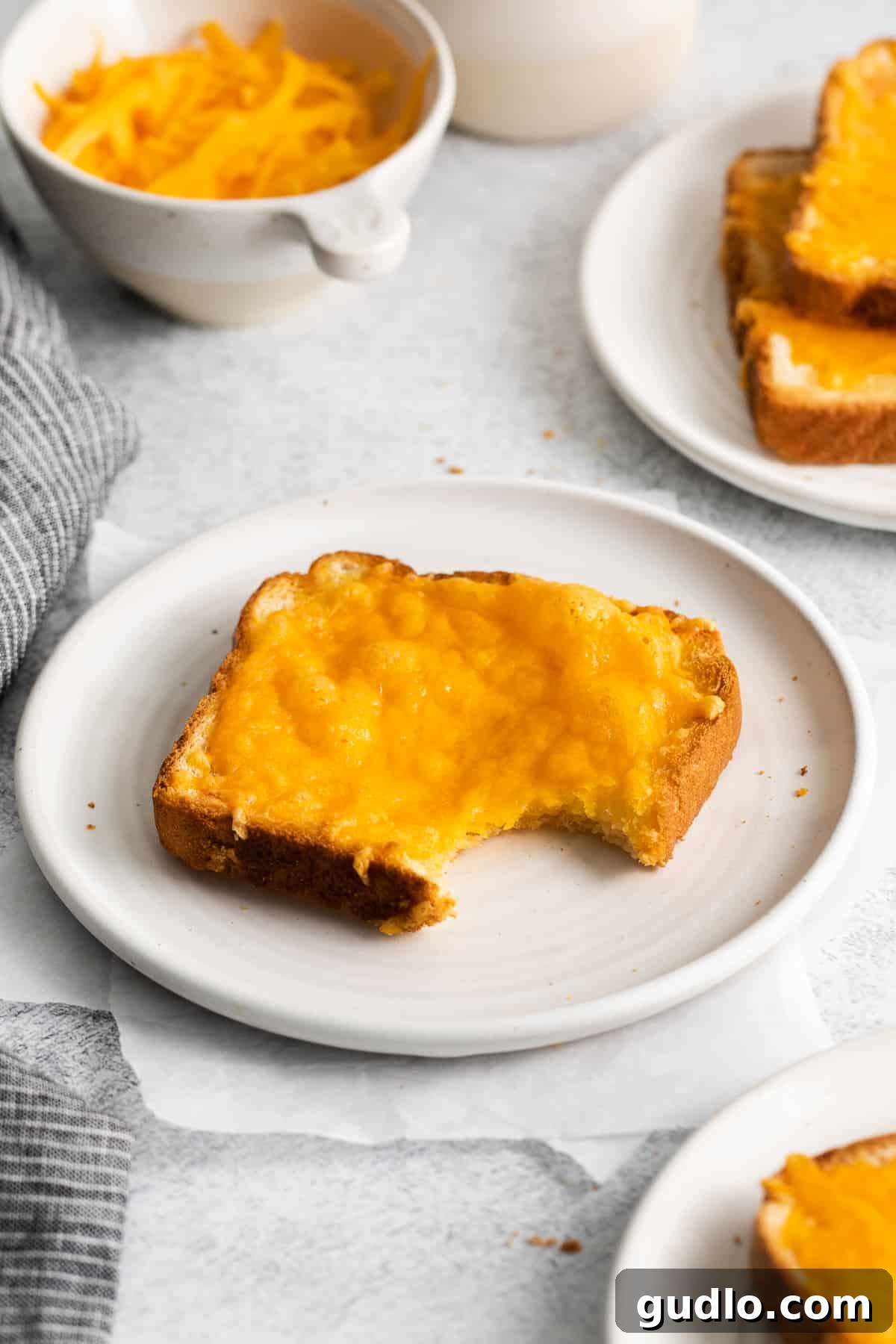 Golden Cheesy Toast 7 A slice of cheese toast with a bite taken out, revealing the soft interior and melted cheese.