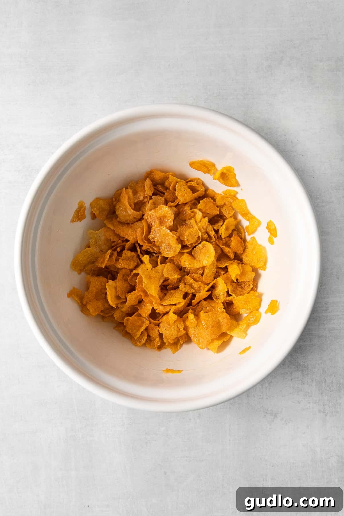 A close-up shot of crispy golden cornflakes in a bowl, ready to be used as a topping.