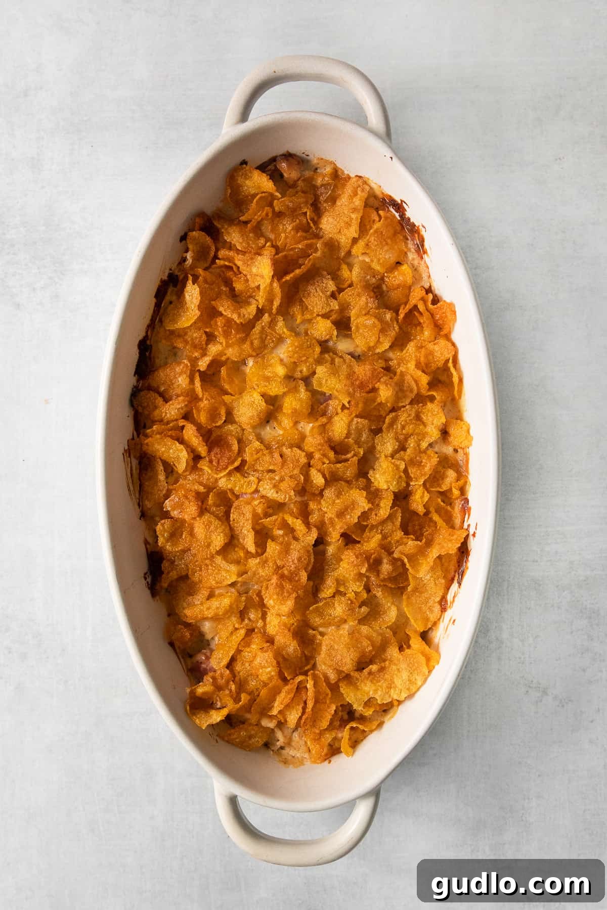 A tantalizing close-up of chicken cordon bleu casserole, generously topped with golden, crispy corn flakes, still in the baking dish.