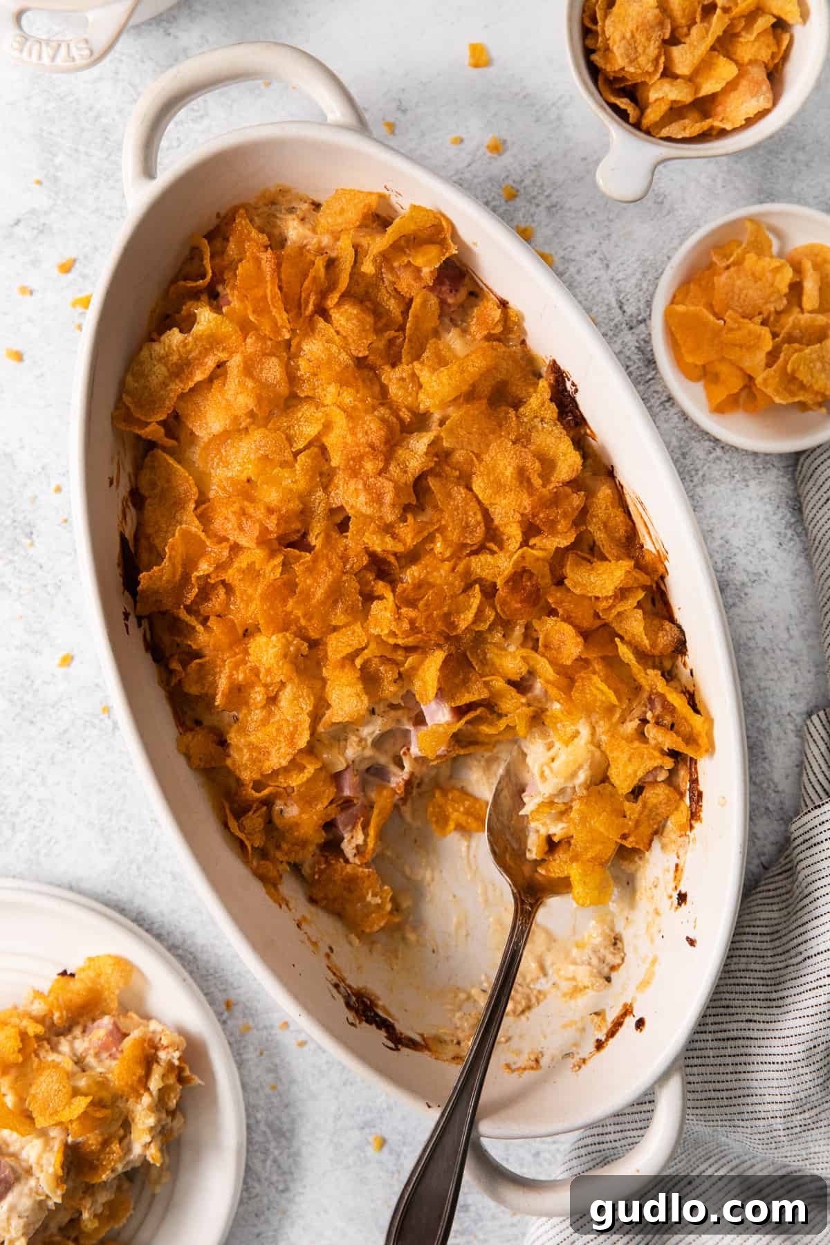 A spoonful of creamy, cheesy chicken cordon bleu casserole, showing the layers of chicken, ham, and melted Swiss, topped with a golden cornflake crust.