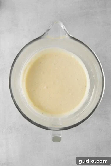 a bowl of creamy cheesecake batter on a gray surface.