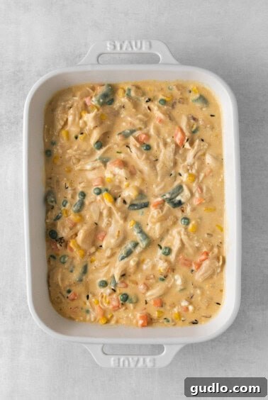 Homestyle Chicken Pot Pie Bake 4 Rich chicken and vegetable filling in a white casserole dish, ready for the puff pastry.