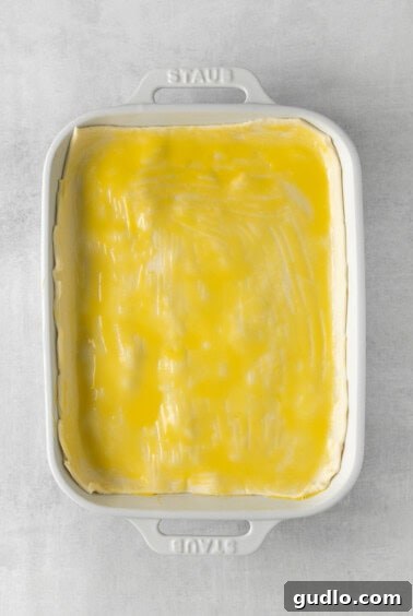 Homestyle Chicken Pot Pie Bake 5 Puff pastry crust brushed with egg wash over chicken pot pie casserole, ready for baking.