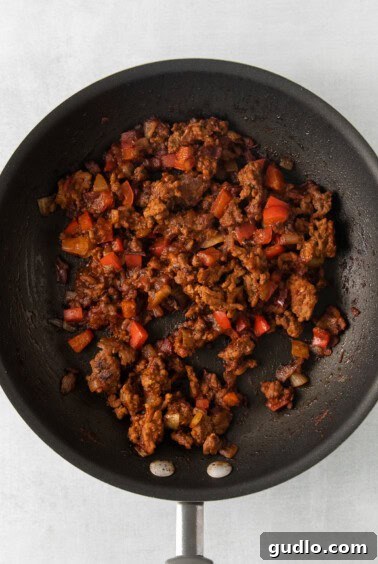 No-Fuss Totchos 4 Ground beef and colorful bell peppers sizzling in a large skillet.
