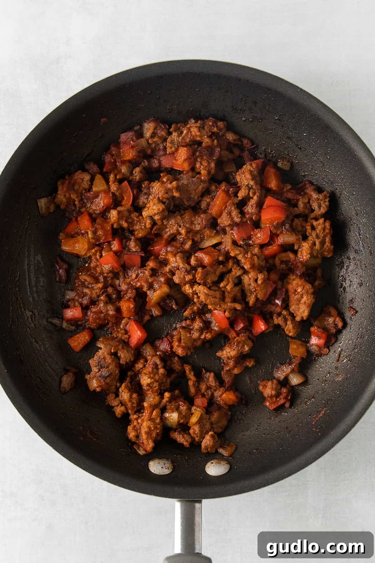 Totchos Beef Filling Ground beef, onions, and peppers simmering in a skillet, filling the kitchen with rich aromas.