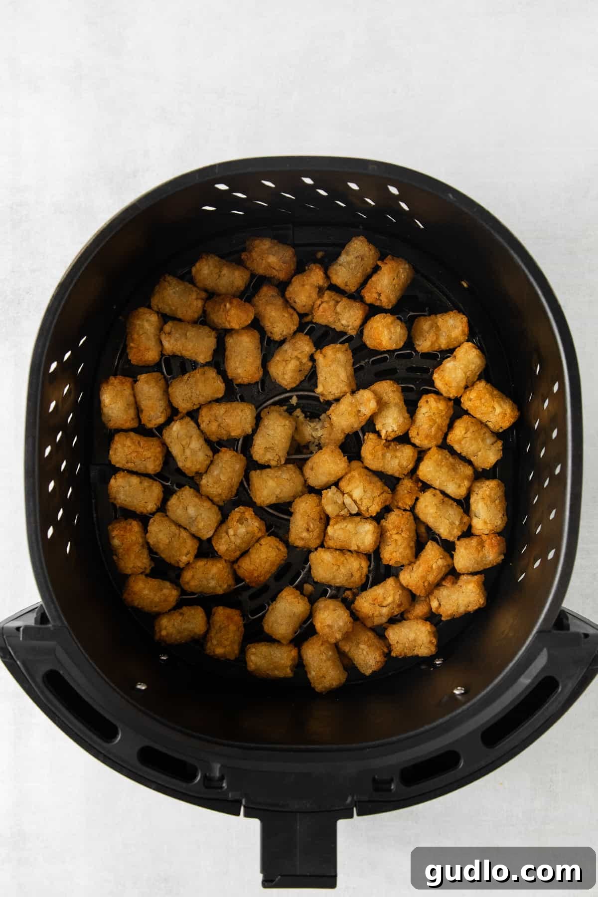 Air Fryer Tater Tots for Totchos Crispy tater tots perfectly golden brown in an air fryer basket, ready for toppings.