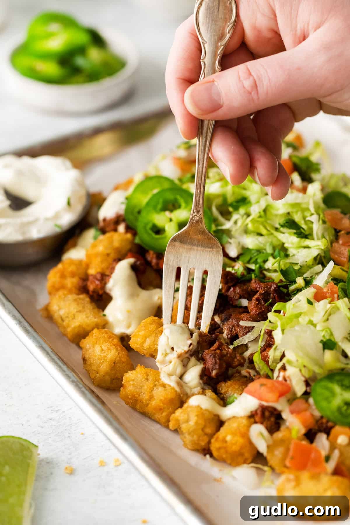 Enjoying Fresh Totchos A totcho on a fork, poised above a full plate, ready to be eaten.