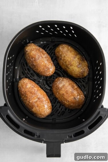 Four air fryer hasselback potatoes seasoned and ready to cook.