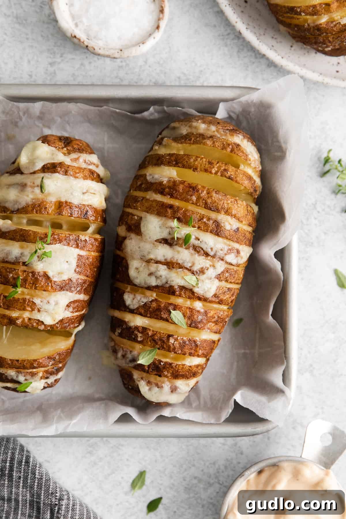 Hasselback Potatoes Ready for Air Frying Crispy hasselback potatoes brushed with butter and seasoning on a baking sheet, ready for the air fryer.