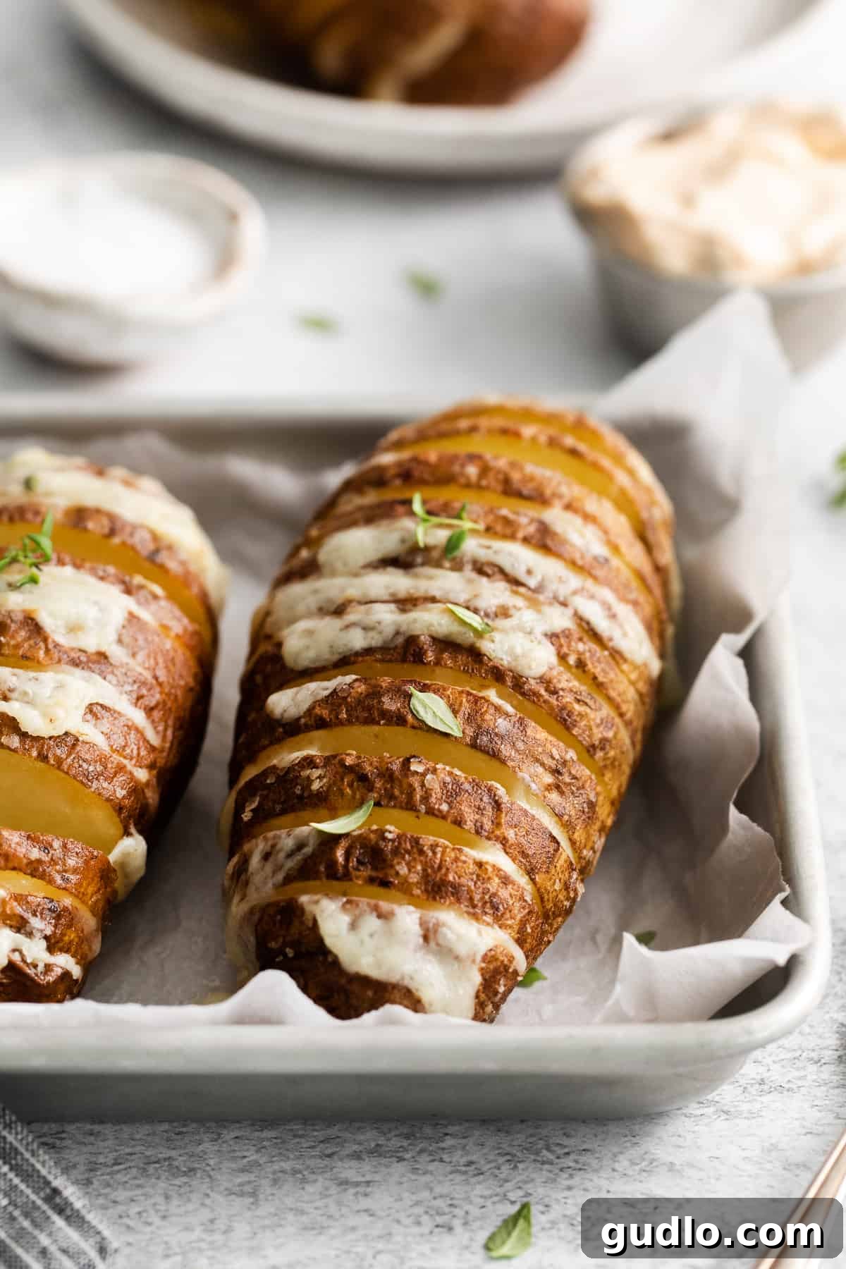 Garnished Air Fryer Hasselback Potatoes A serving of air fryer hasselback potatoes on a white plate, garnished with fresh green onions.