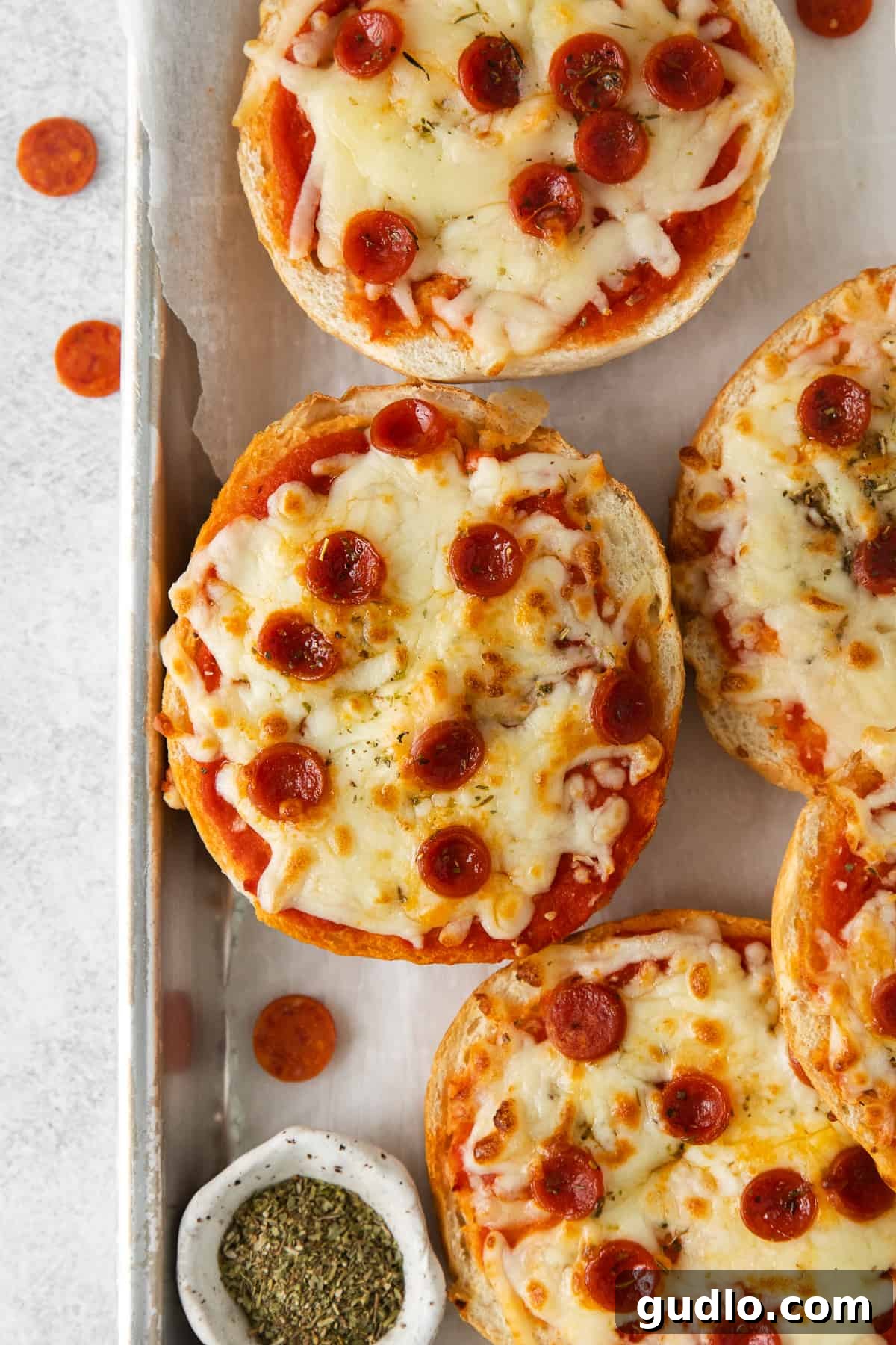 Delicious Air Fryer Pizza Bagels: quick, cheesy, and easy to make at home. Golden brown air fryer pizza bagels on a baking sheet, topped with melted cheese and mini pepperoni, ready to be served.