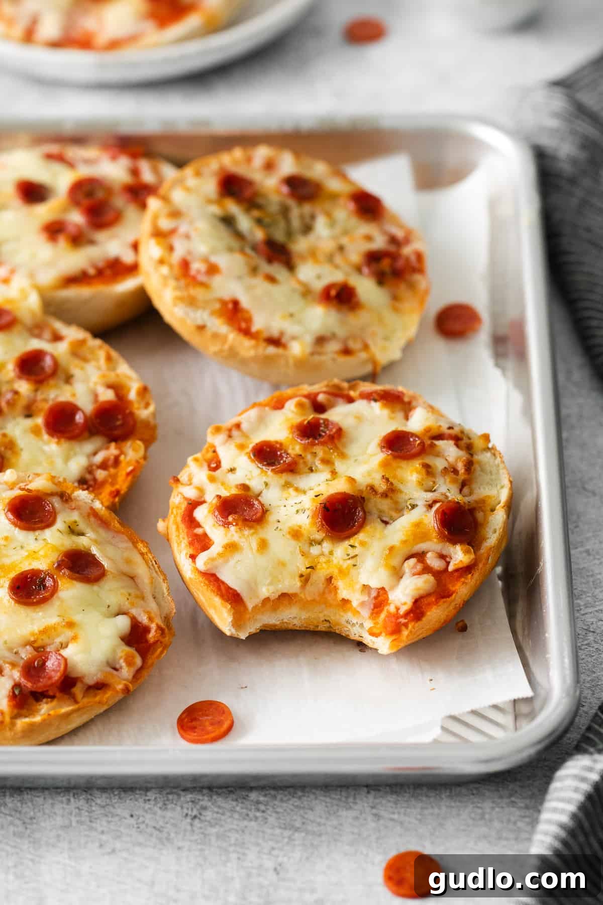 Close-up of a delicious pizza bagel after air frying, showing its irresistible texture. A close-up shot of a perfectly cooked air fryer pizza bagel with a bite taken out, revealing the gooey melted cheese, crispy bagel, and delicious pepperoni inside.