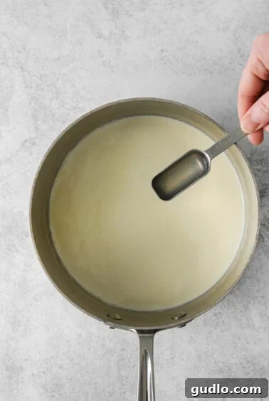 Lemon juice being added to simmering heavy cream in a saucepan.