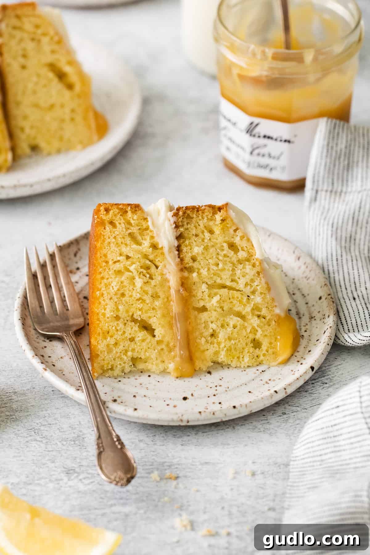 Perfect Slice of Limoncello Mascarpone Cake A close-up of a perfect slice of Limoncello Mascarpone Cake on a pristine white plate, garnished with lemon zest.