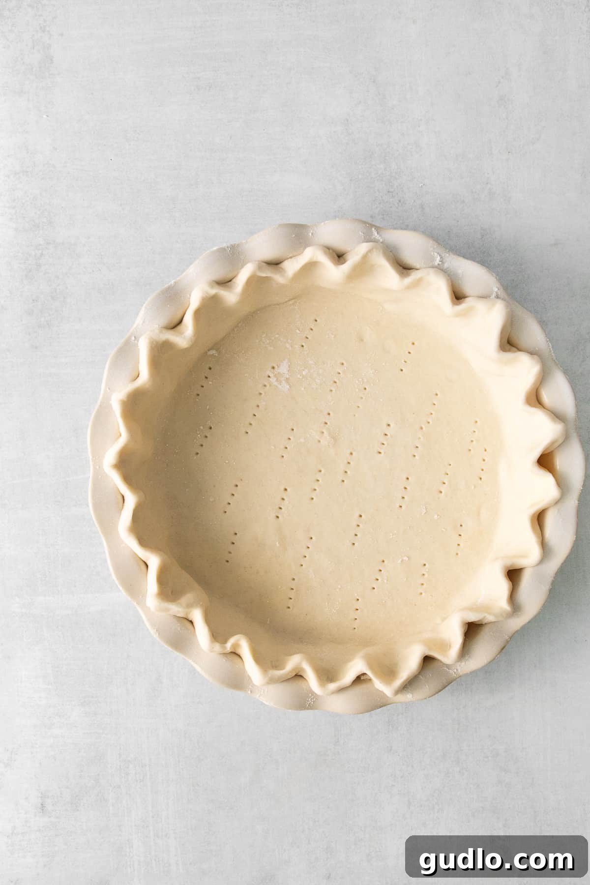 Our easy Quiche Lorraine recipe is the perfect dish for your next brunch! Made with fluffy eggs, cheese, bacon and onions. A freshly prepared homemade pie crust, perfectly crimped and ready for filling, set in a pie dish.
