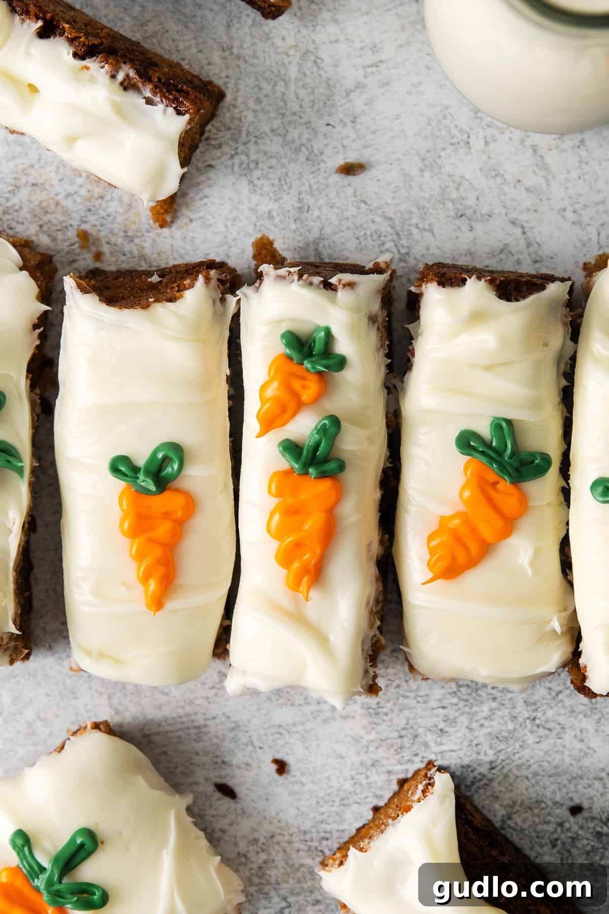Perfectly sliced homemade carrot cake bars with a thick layer of cream cheese frosting on a white platter, ready to be served.