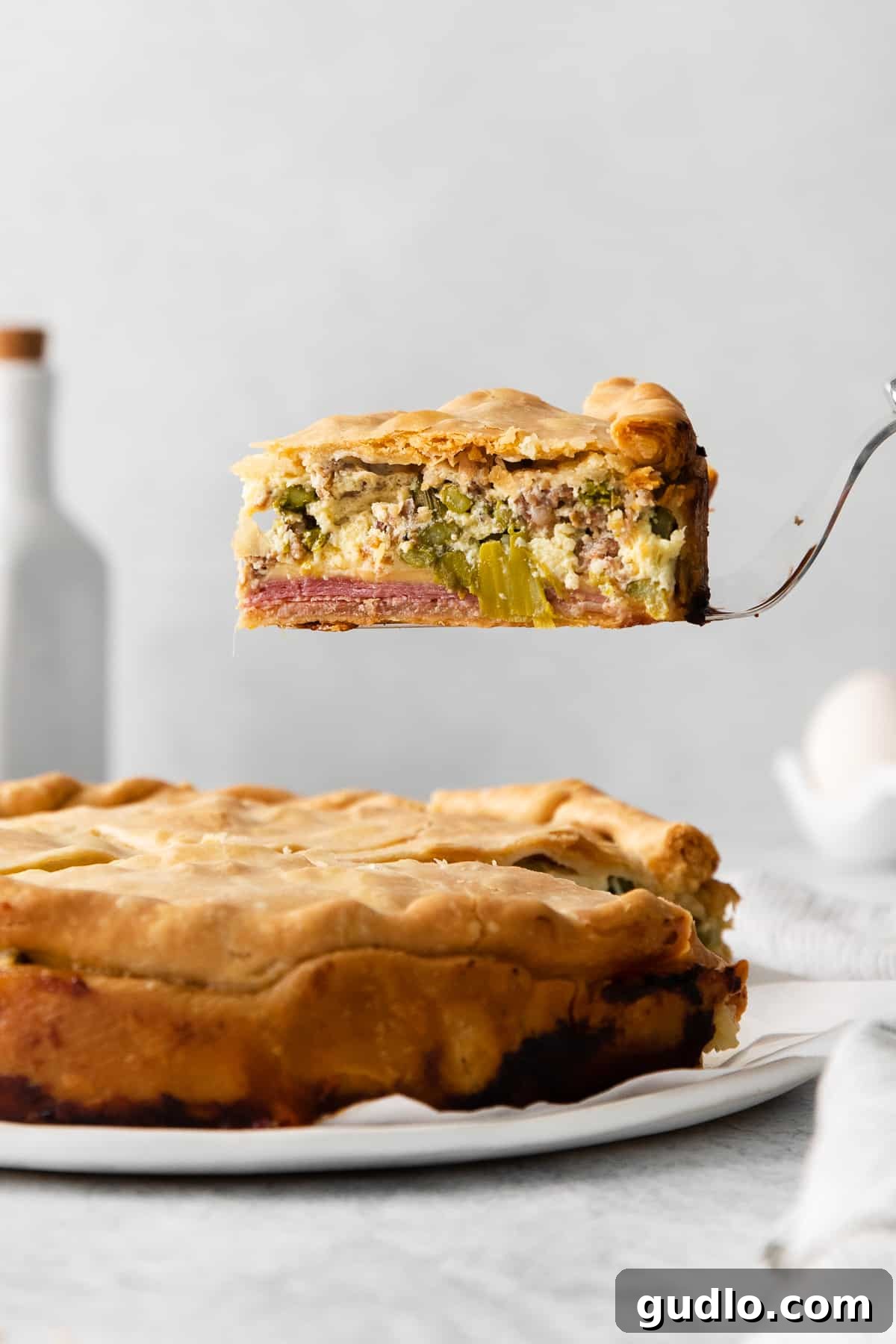 A perfectly sliced piece of Italian Easter pie on a serving spatula, showcasing its layers of meat, cheese, and filling.
