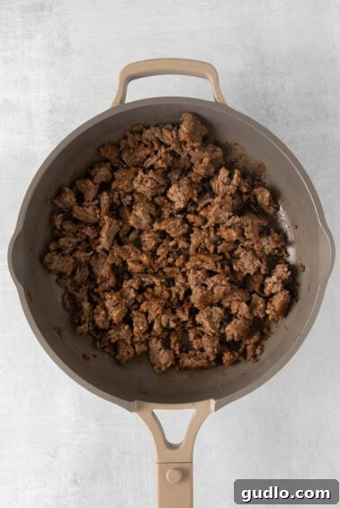 A frying pan filled with crumbled, browned ground Italian sausage.