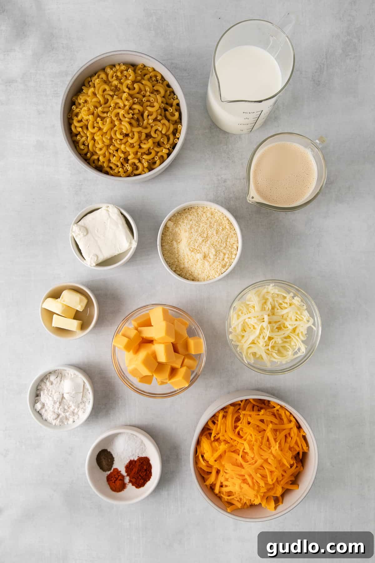 Bowls filled with the featured ingredients for Southern baked mac and cheese, including pasta, milk, butter, and various cheeses.