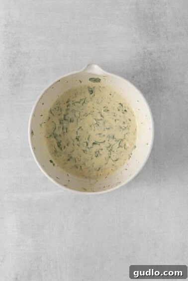 Creamy English Pea Salad 10 A white bowl with a creamy green sauce, ready to be mixed into the salad.