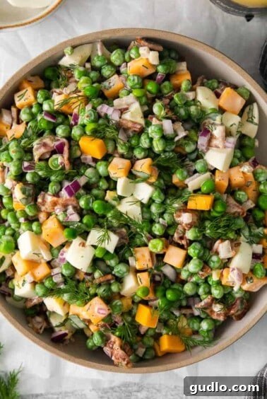 Creamy English Pea Salad 12 English pea salad in a bowl, garnished with fresh herbs, ready for serving.
