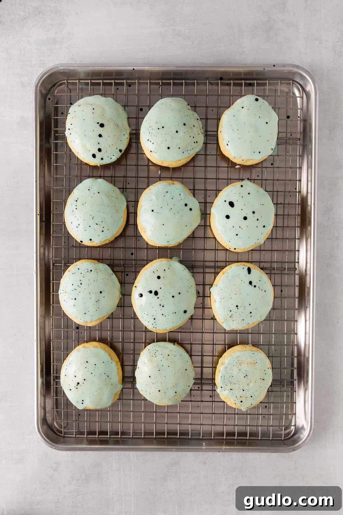 Glazed lemon ricotta cookies topped with sprinkles on a cooling rack.