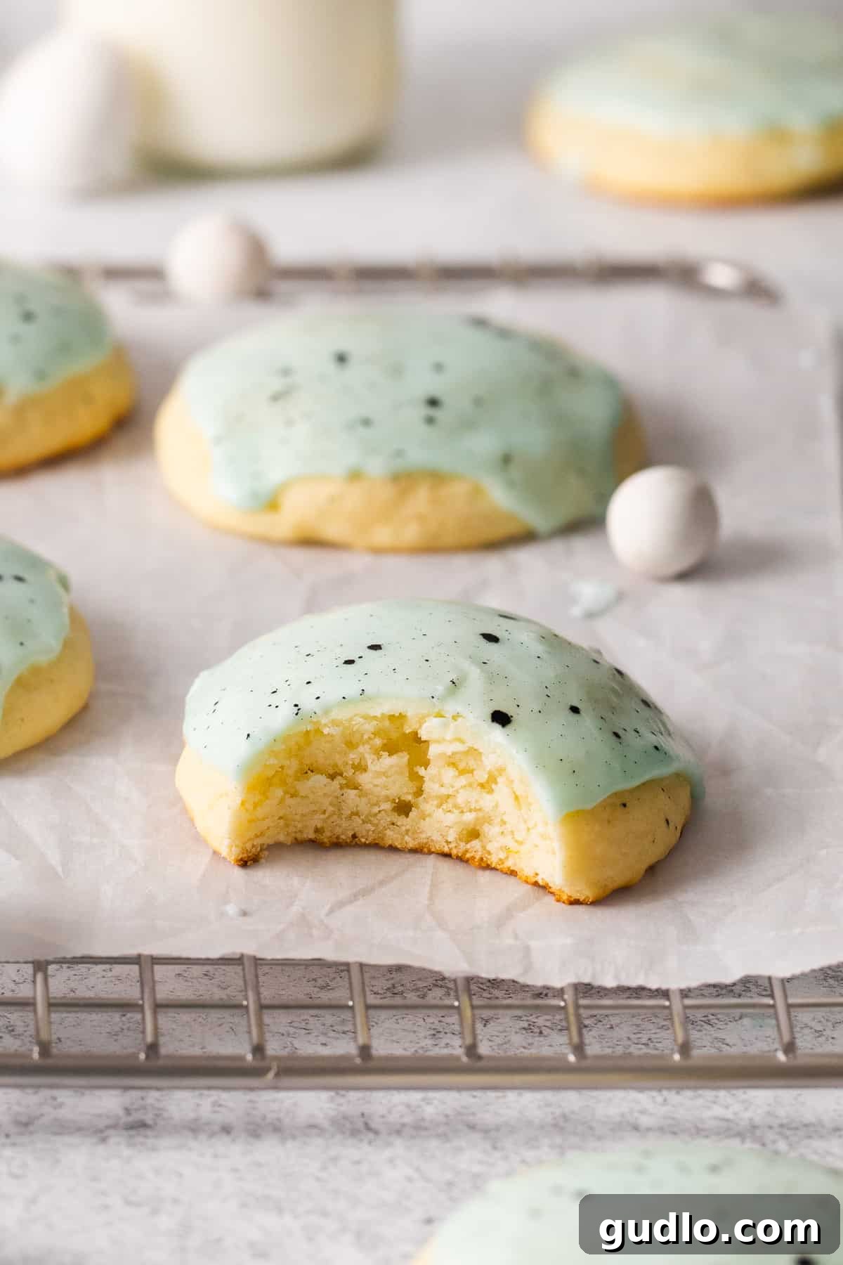 A beautifully decorated lemon ricotta cookie with a bite taken out, showing its soft interior.