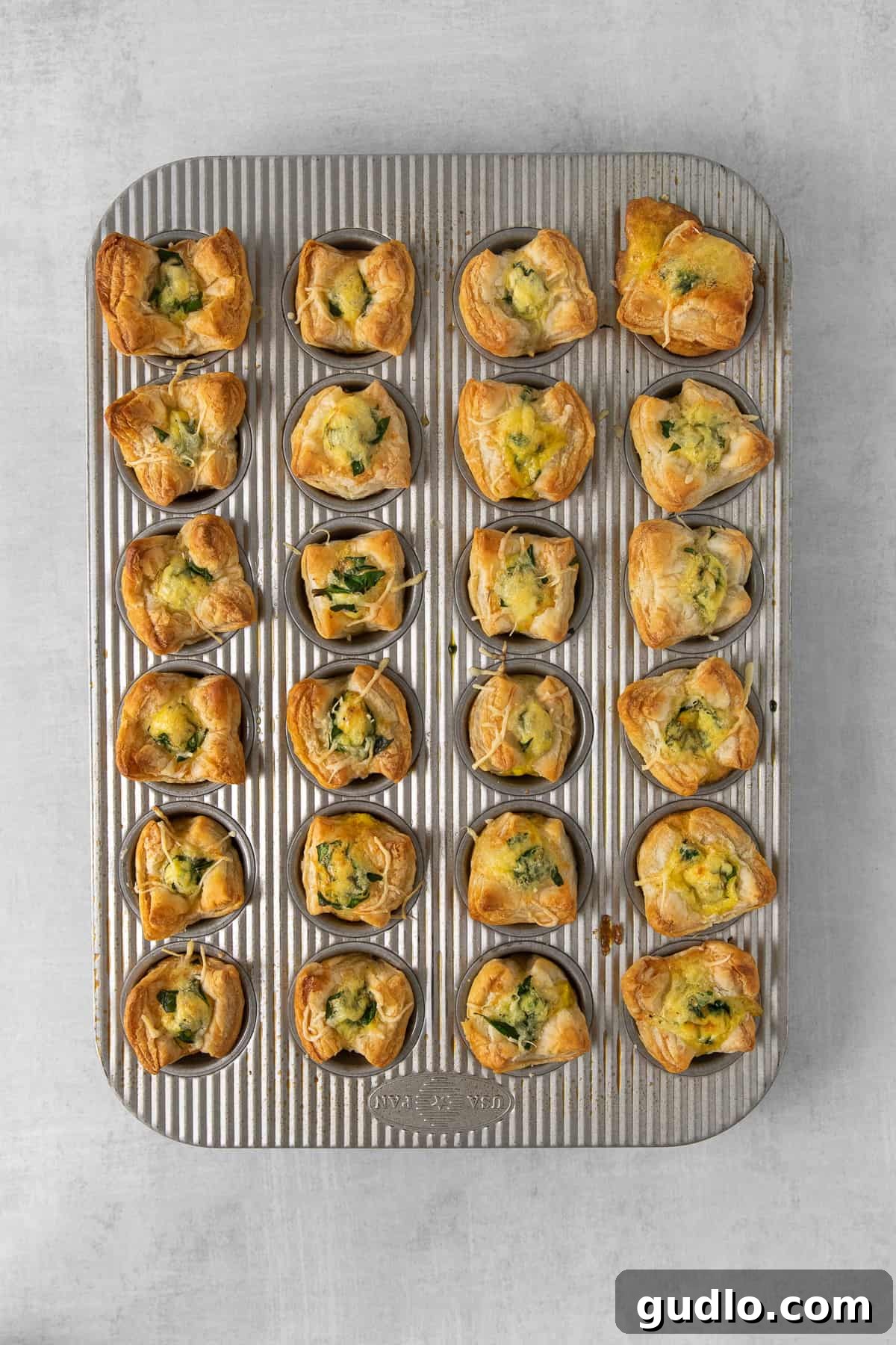 This mini quiche florentine offers savory, cheesy goodness with every bite! Enjoy a tasty blend of spinach, gruyere cheese, and creamy egg filling enveloped in a flaky pie crust that will take you to breakfast heaven. Mini quiche florentine in cooked in a mini muffin tin.