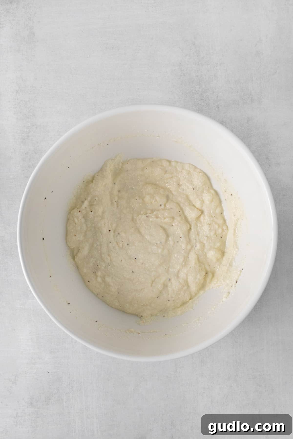 A creamy ricotta sauce being prepared in a bowl, showing its smooth texture.