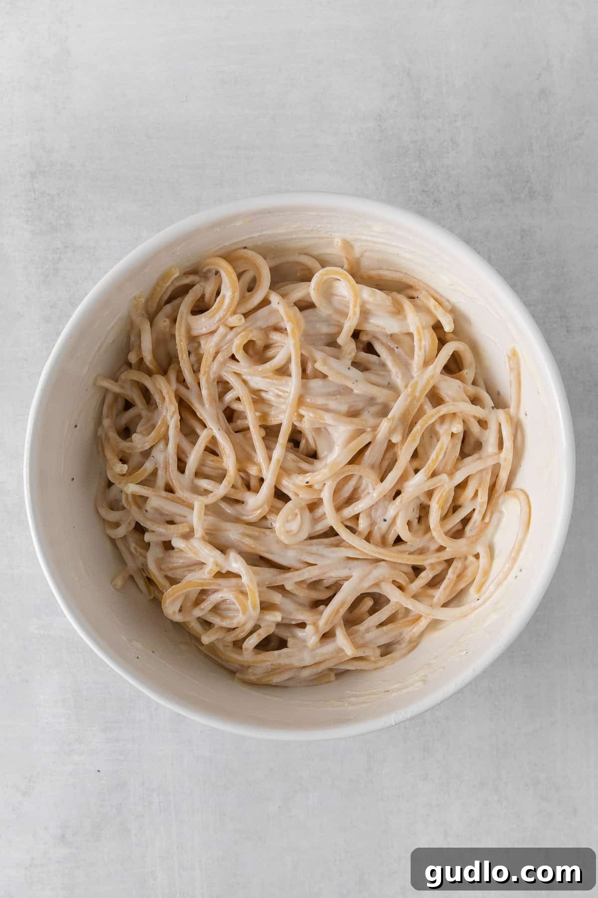 A fork taking a bite from a bowl of pasta with ricotta sauce.