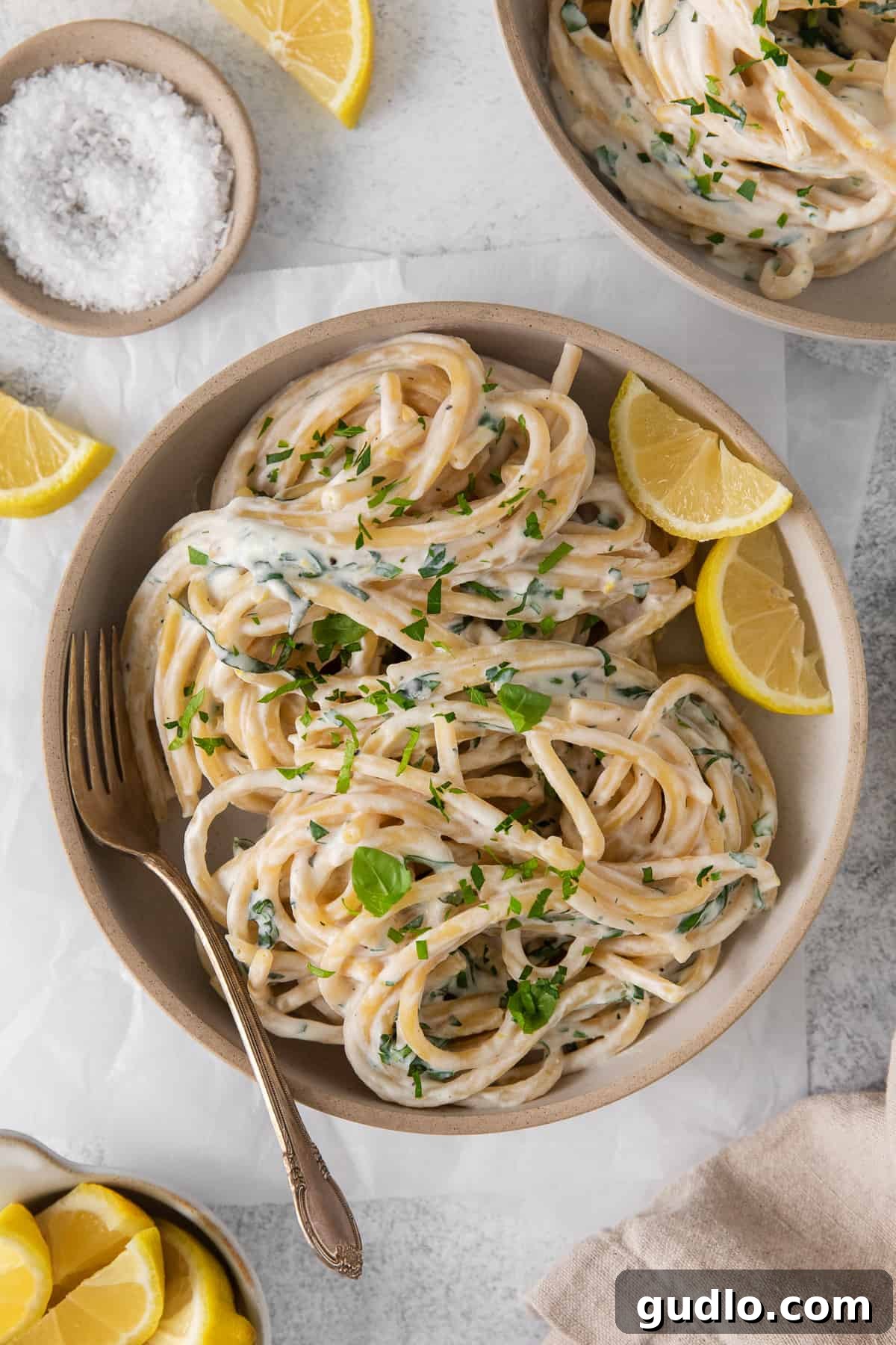 Lemon ricotta pasta in a bowl with a fork, garnished with fresh lemon slices and herbs.