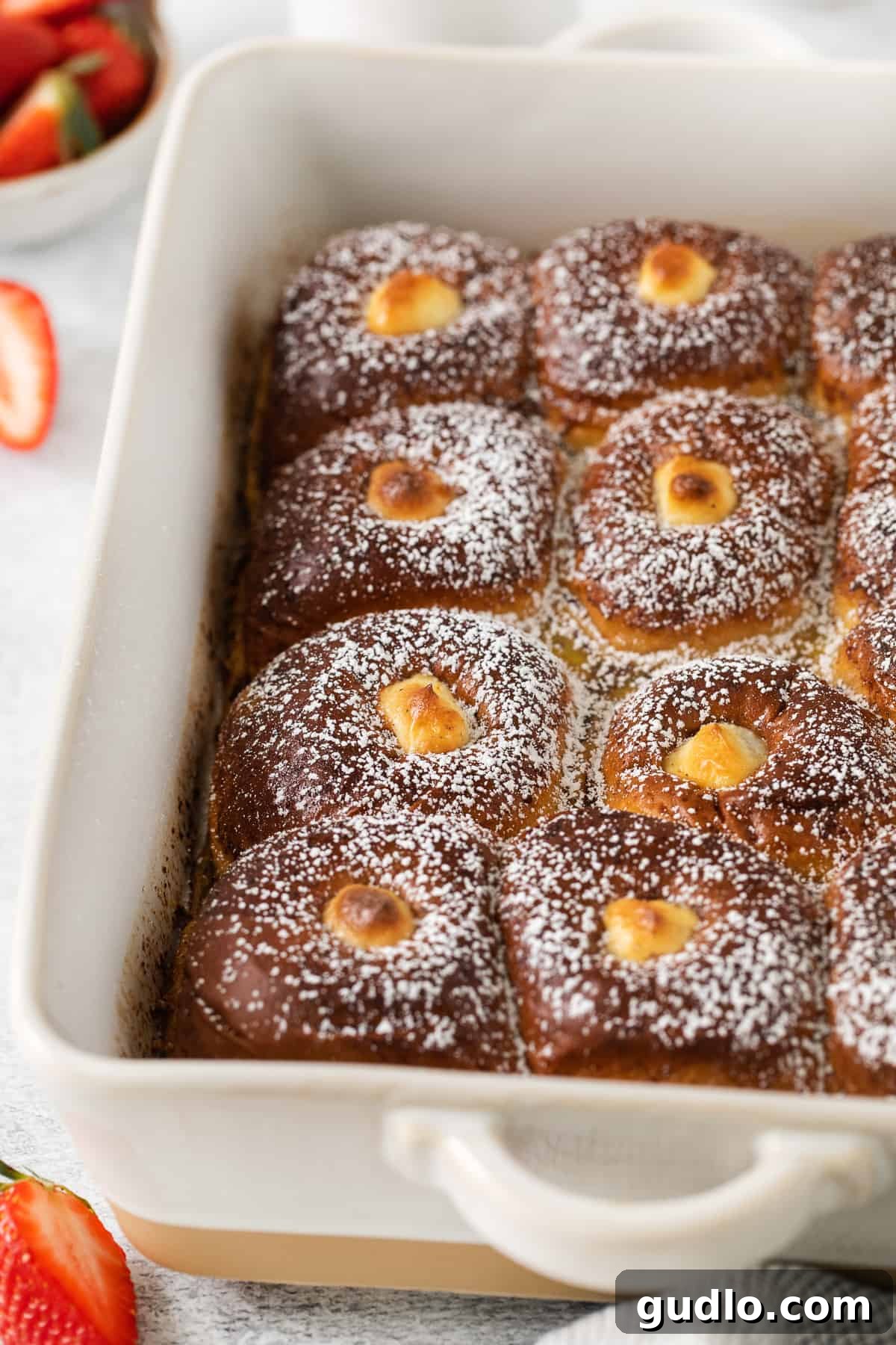 Decadent Stuffed Hawaiian Roll French Toast for Brunch Golden-brown Stuffed Hawaiian Roll French Toast baking in a casserole dish, ready to be served.