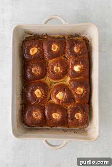 Buns soaking in liquid in a baking dish, covered with plastic wrap.