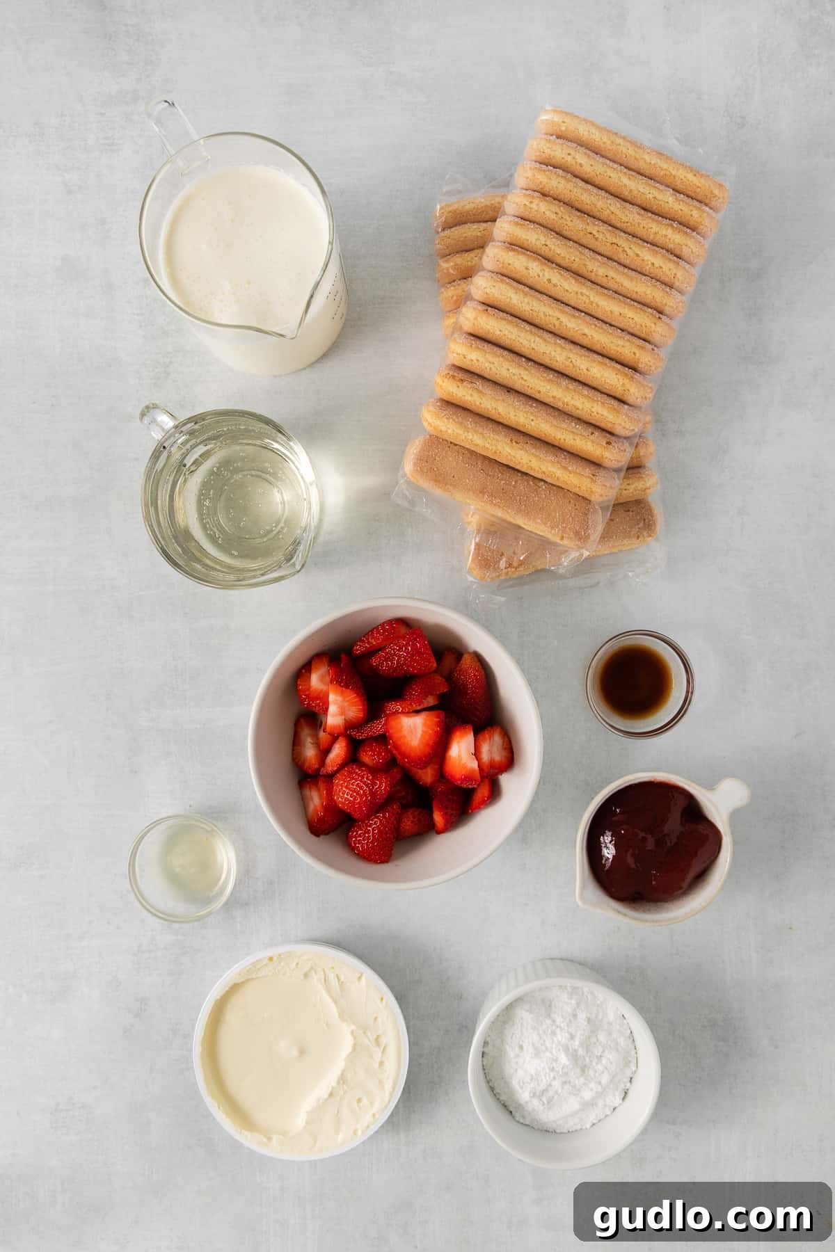 This homemade strawberry tiramisu has layers of flavorful mascarpone filling and prosecco-drenched ladyfingers. It is a fruity twist to this traditional no-bake dessert. Ingredients for strawberry tiramisu laid out in bowls, including ladyfingers, strawberries, mascarpone, and cream.